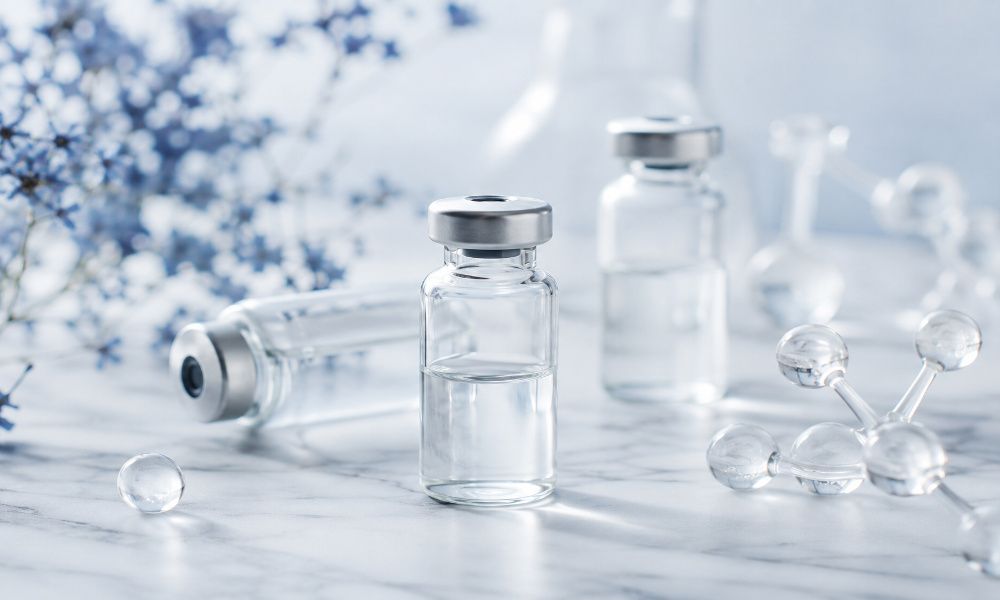 Clear glass vials and molecular models on a marble surface, representing peptides for a beginner's guide